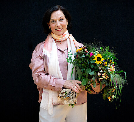 Christine Camillo mit Blumenstrauß vor schwarzem Hintergrund